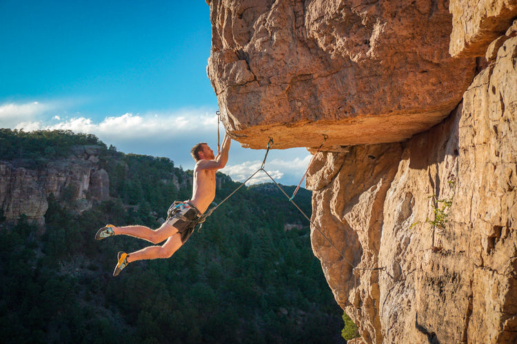 harnessed-person-holds-onto-the-edge-of-a-rock-cliff - ExtremeGear.org